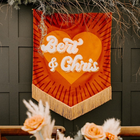 Decorative wall hanging with 'Bert & Chris' text above a floral arrangement.